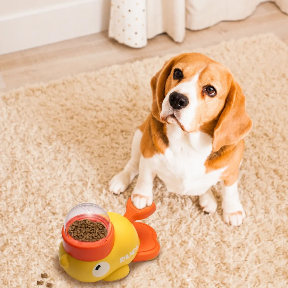 Close-up of a yellow duck treat dispenser with a dog paw pressing the orange lever 2